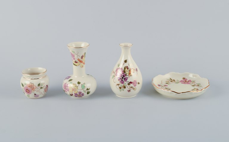 Zsolnay, Hungary, four-piece porcelain set consisting of three vases and a small dish. Hand-painted with flower motifs and insects on a cream-colored background.
